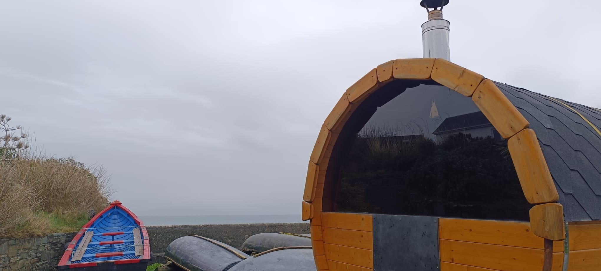 Detail of the barrel sauna with a currach beside it