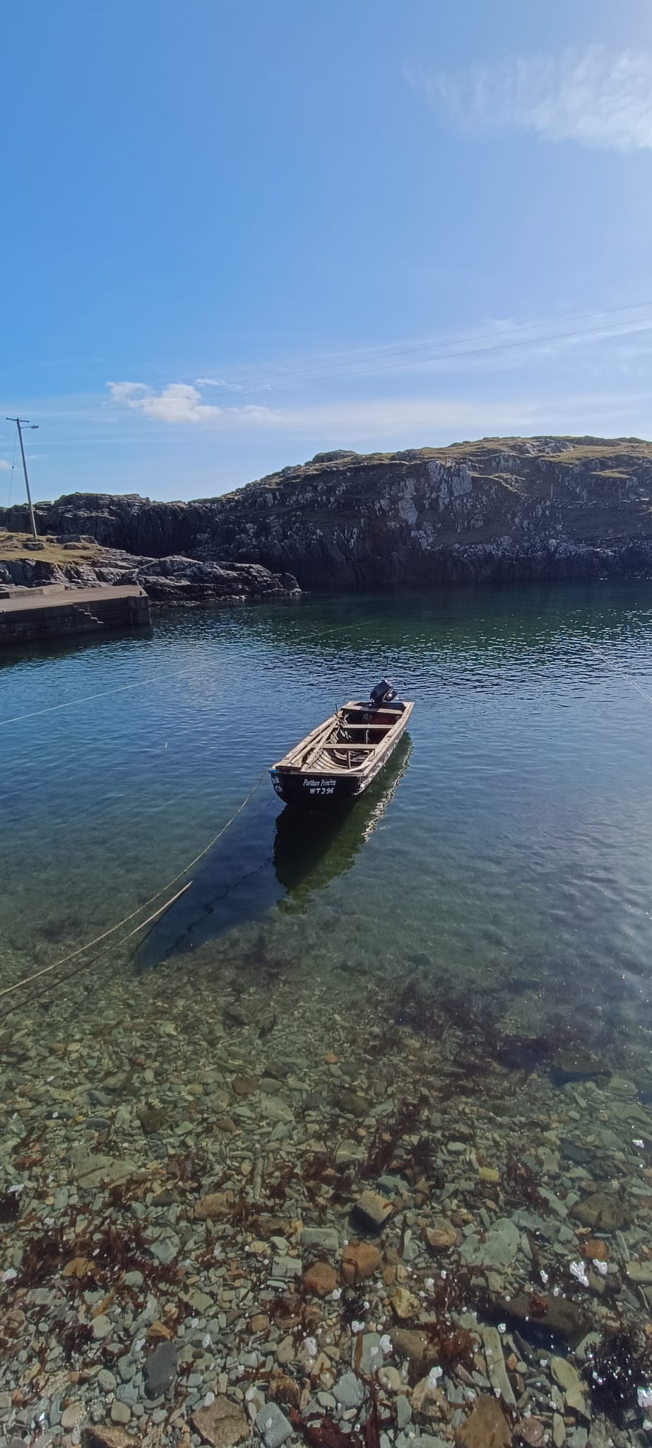 Boat at anchor with the pier and rocks beyond