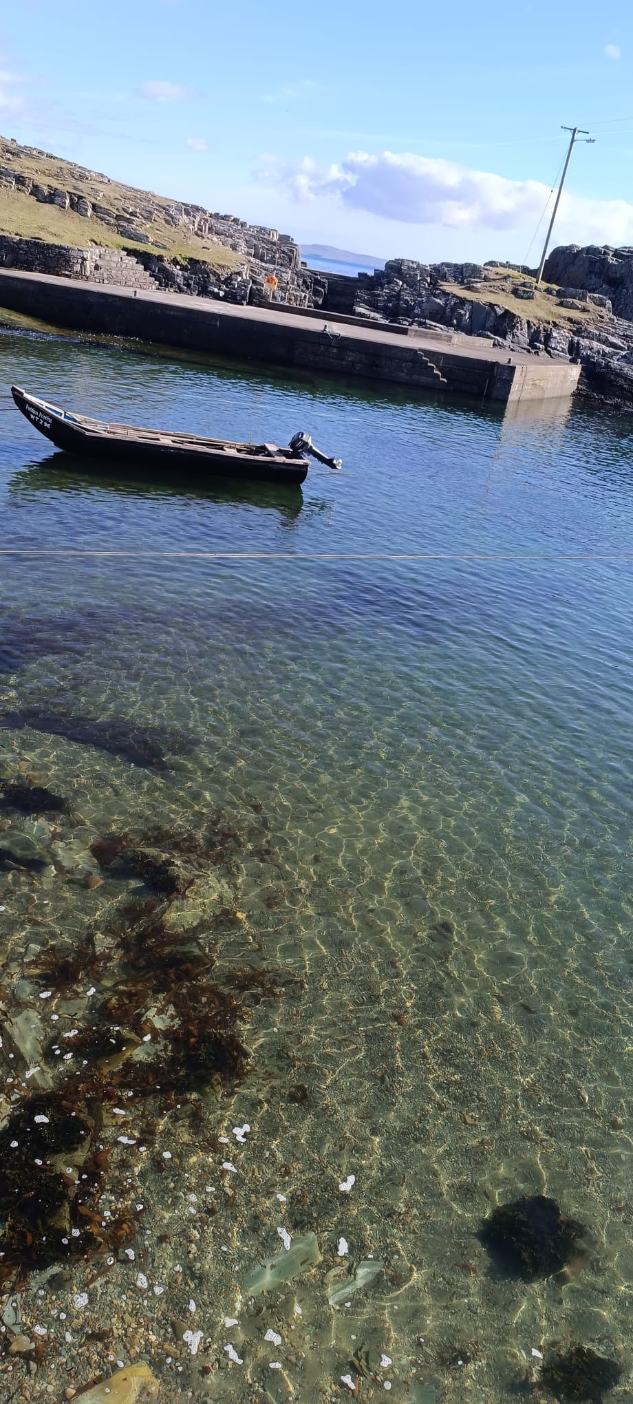 Boat in the harbour, every stone of the seabed visible