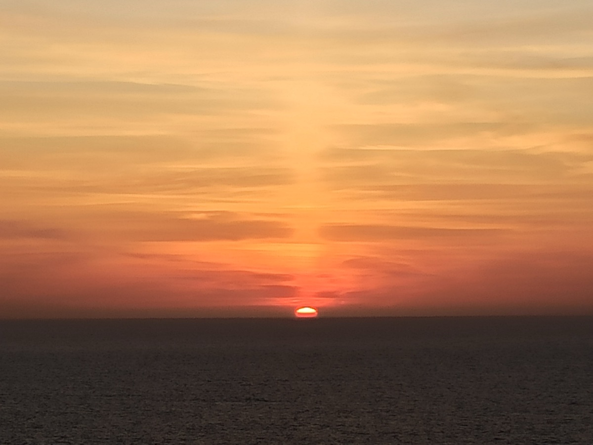 Sun dropping below the Atlantic horizon in a wash of amber and rose