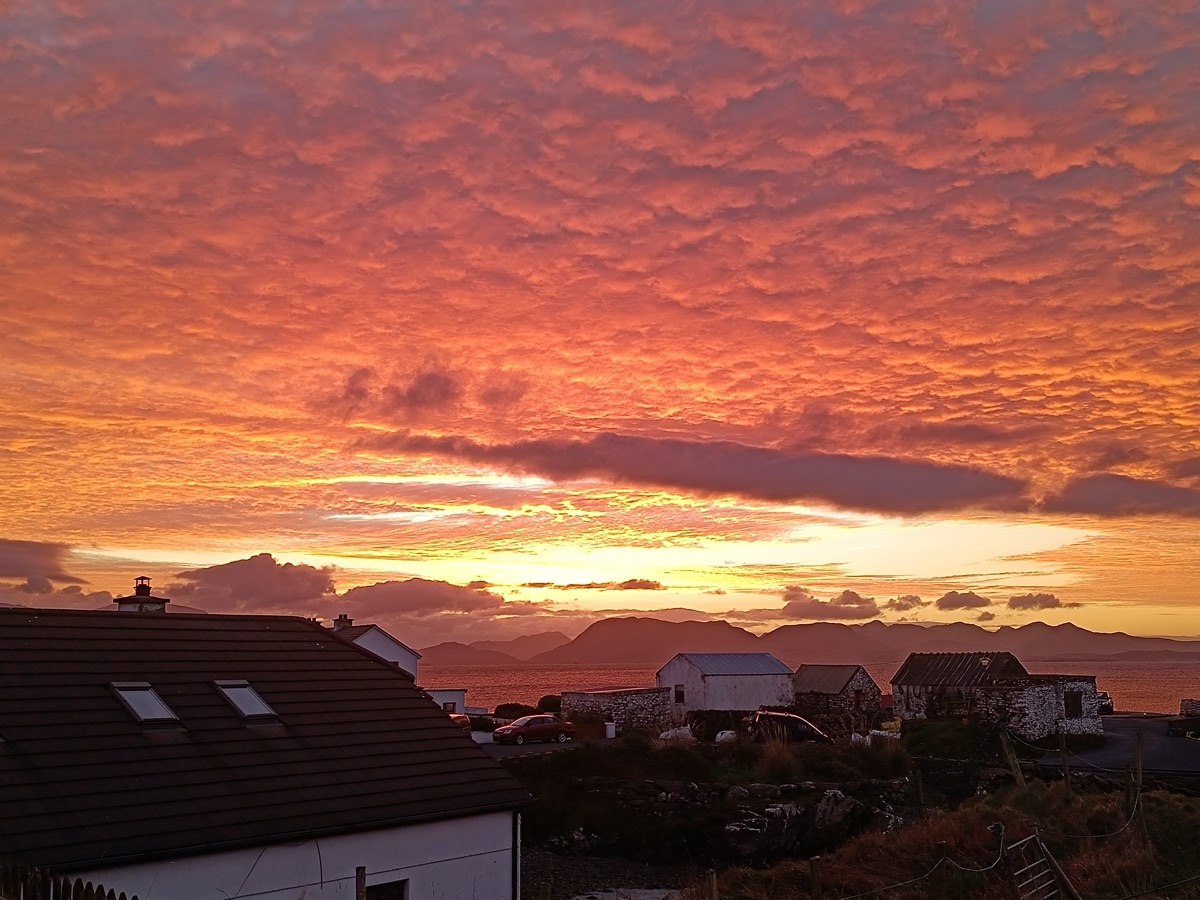Blazing red mackerel sky at sunset over the island rooftops and stone sheds