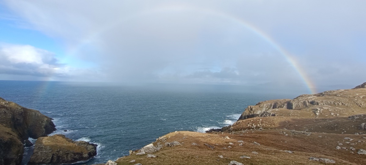Full rainbow arcing over the sea cliffs on a grey January afternoon